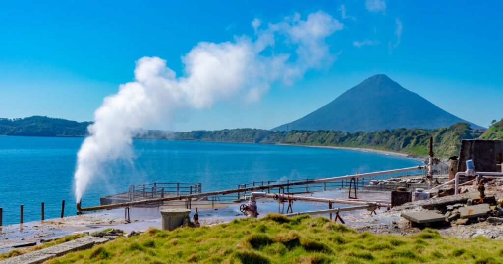 海辺の温泉地から立ち上る湯気と開聞岳を望む景色