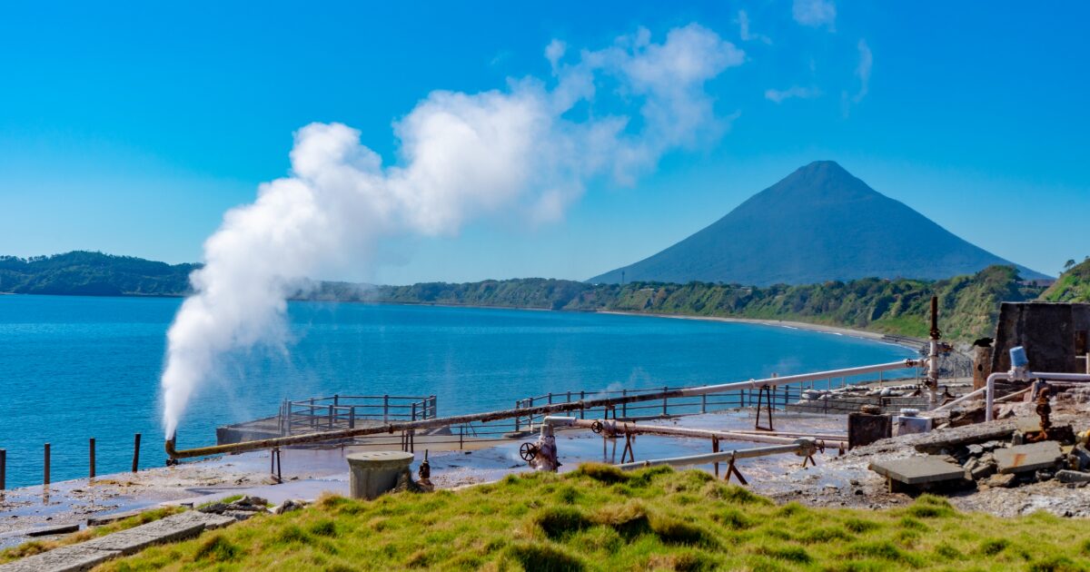 海辺の温泉地から立ち上る湯気と開聞岳を望む景色