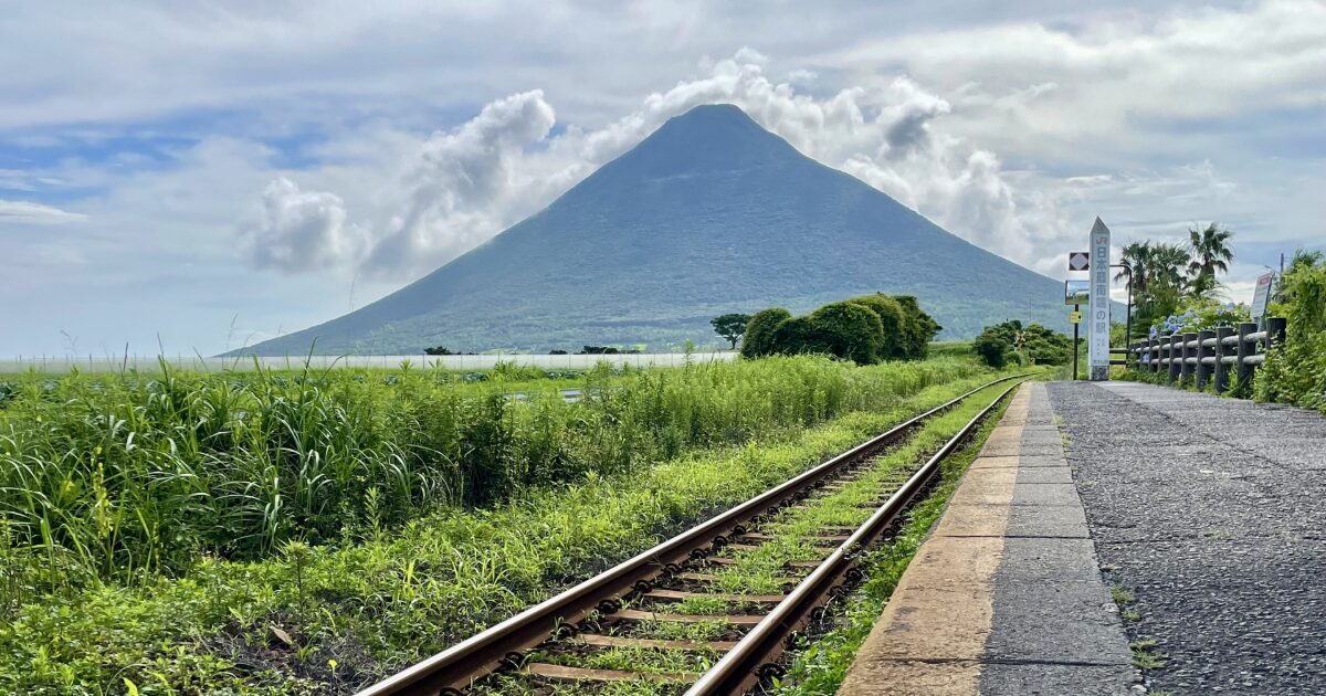 ローカル線の線路と開聞岳が続くのどかな風景