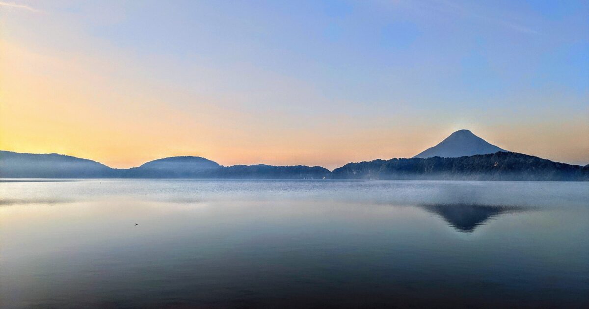 湖面に映る開聞岳と朝焼けの幻想的な風景