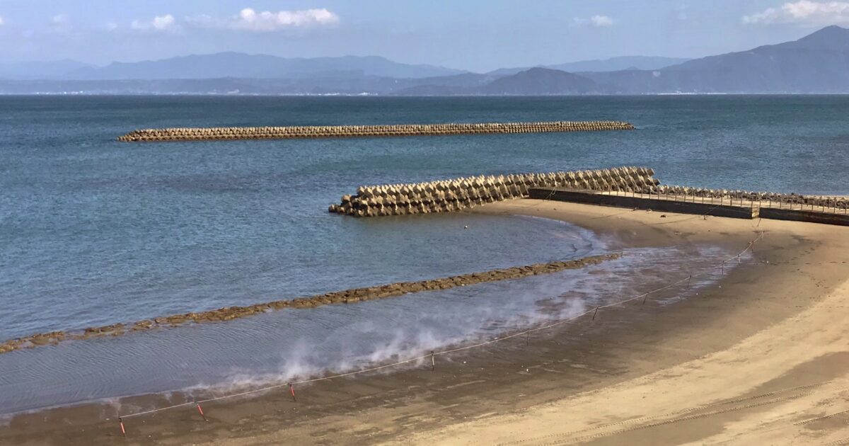 海岸沿いに広がる砂むし温泉の湯気と静かな湾の風景