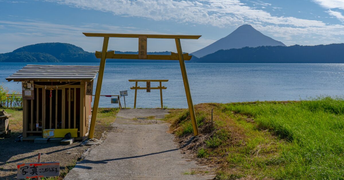 湖畔の鳥居と開聞岳を望む神秘的な風景