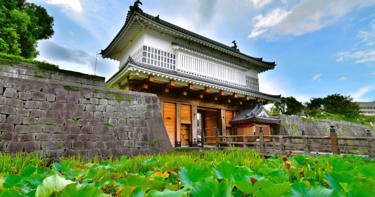 石垣に囲まれた城門と蓮池が広がる歴史的景観