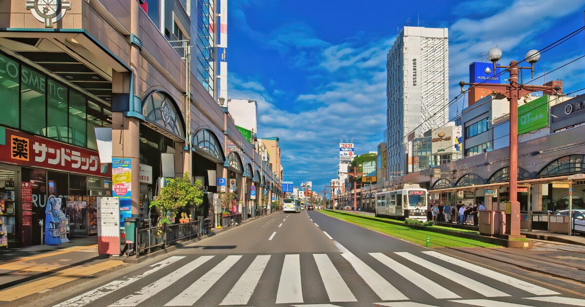 鹿児島市内の路面電車と商店街が続く道路風景