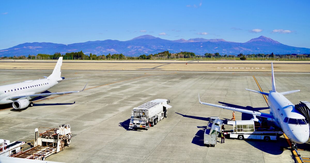空港の駐機場に並ぶ旅客機と霧島連山の景色