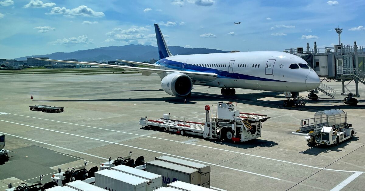 空港の滑走路に駐機する旅客機と地上作業車