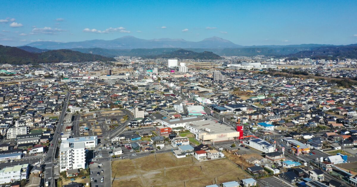 霧島連山を背景にした霧島市街地の空撮景観