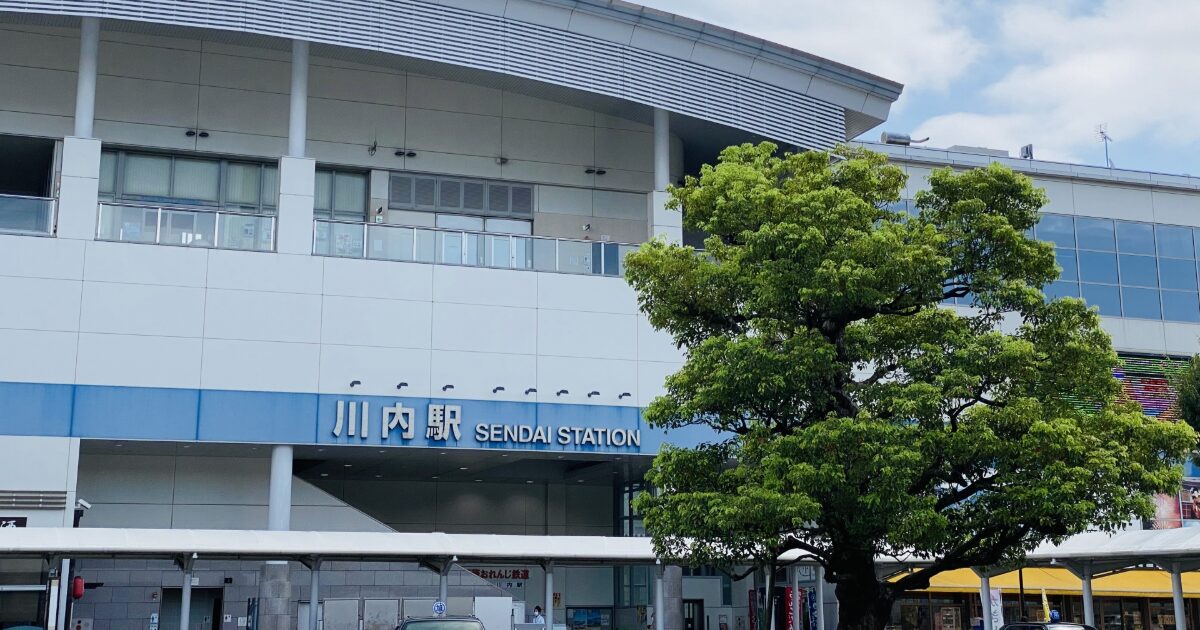 大きな街路樹越しに見る川内駅の駅舎正面